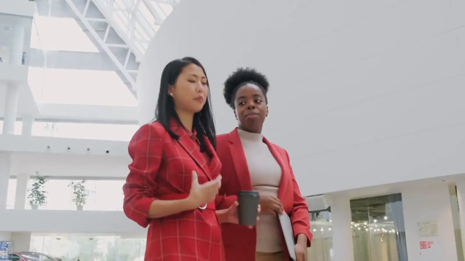 Two colleagues in conversation as they walk through a bright, modern office